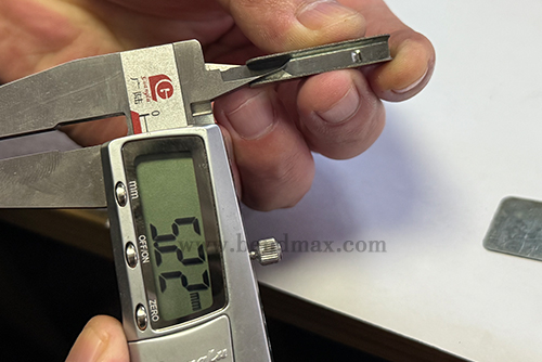 Digital caliper measuring a critical dimension of a custom metal part-1